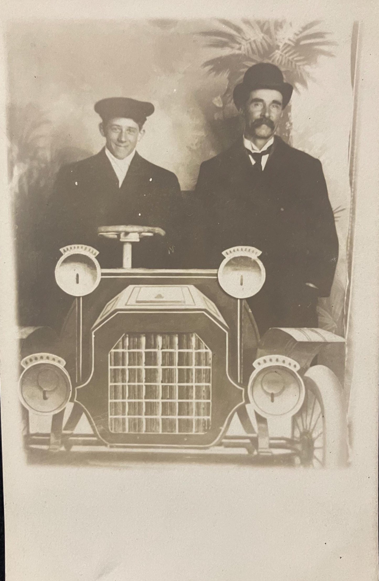 RPPC - Men Posing in a Photographer's Prop Car - One in a Dapper Driving Outfit, the second looking Wealthy and Wise - Likely a Parody Photo